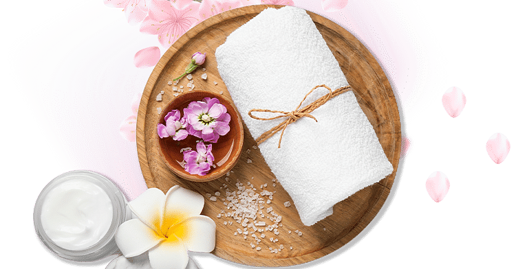 Spa essentials arranged on a wooden tray with flowers and petals, creating a serene and inviting atmosphere