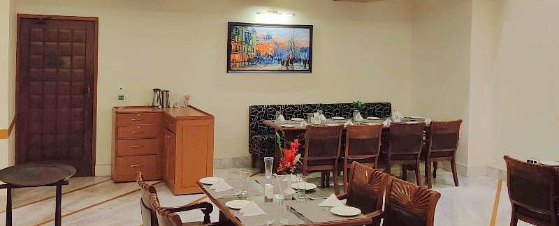 Corner view shot of a brightly lit dining area of the Gold Plate restaurant with central air-conditioning and a small cabinet in the corner of the restaurant - Hotel Gold, Panipat