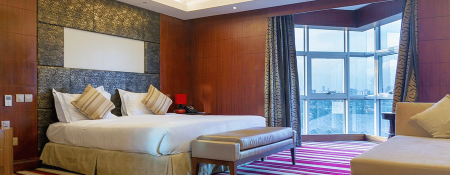 King size bed with striped carpet in a well lit bed room at The Boma Nairobi.