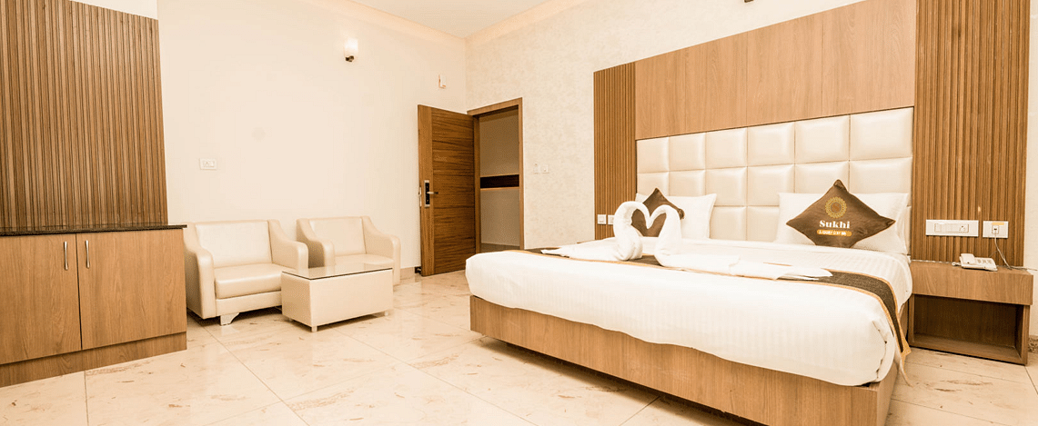 Super Deluxe Room With Balcony featuring a king size bed, a seating area, and minimalist decor.- Sukhi - A Luxury Stay Inn, Chikkamagaluru 