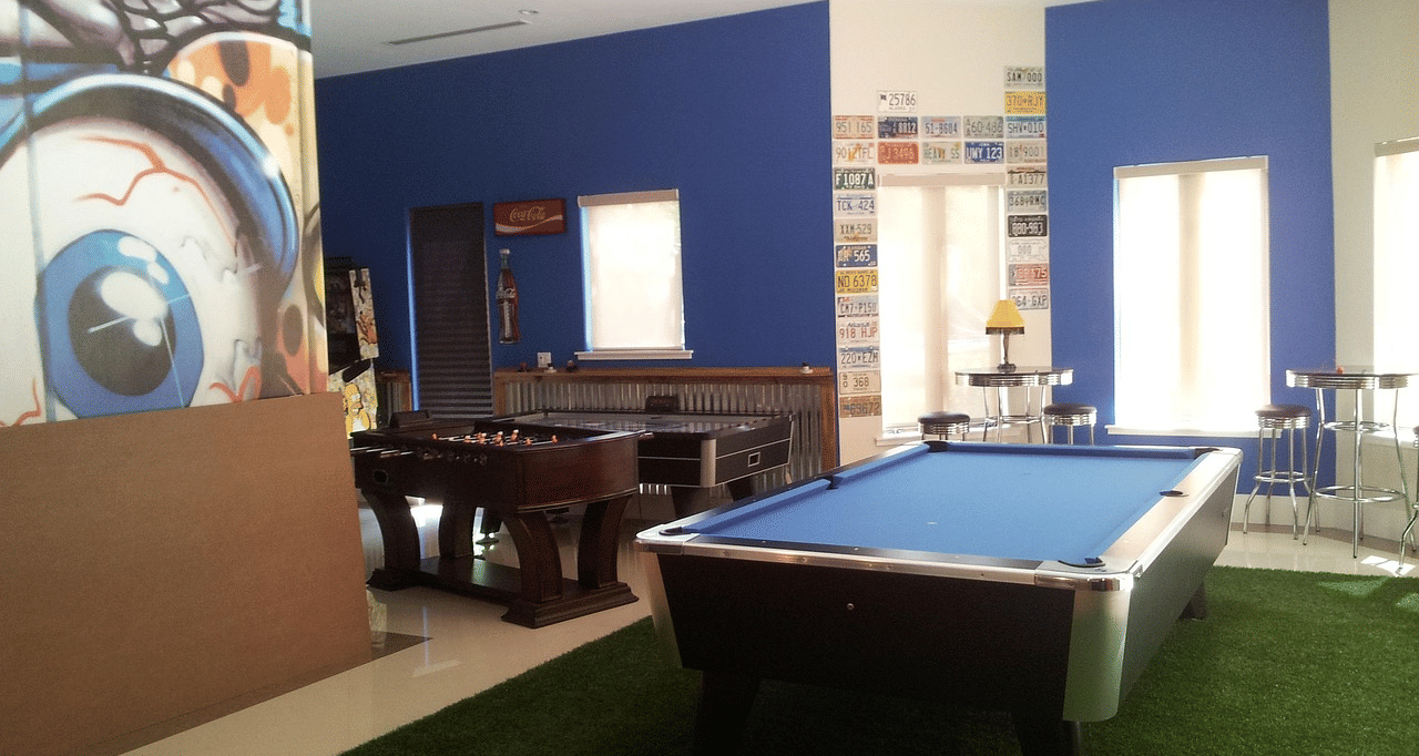 A room painted in blue featuring graffiti on the wall and a pool table.