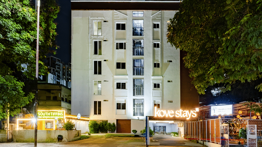 Multi-storey facade, entryway, and Claysutra Pottery Studio And Cafe of Kove Smart Stays as seen from the exterior during the night.