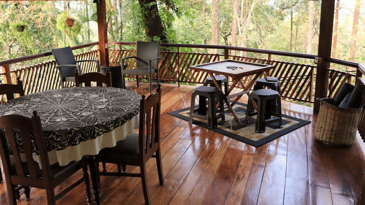 A platform with tables, chairs and carrom board, on a wooden floor.