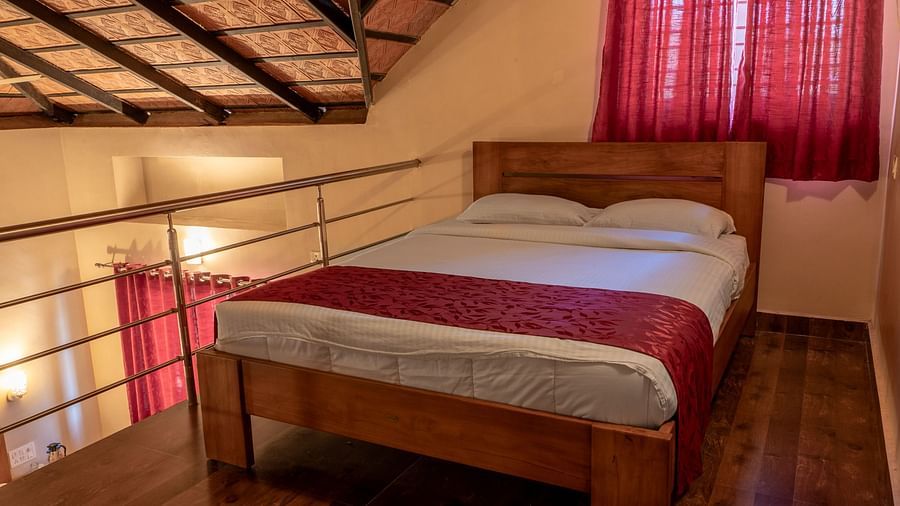 Attic Villa features a bed with red accents and an open ceiling design | Woodstock Resorts, Coorg