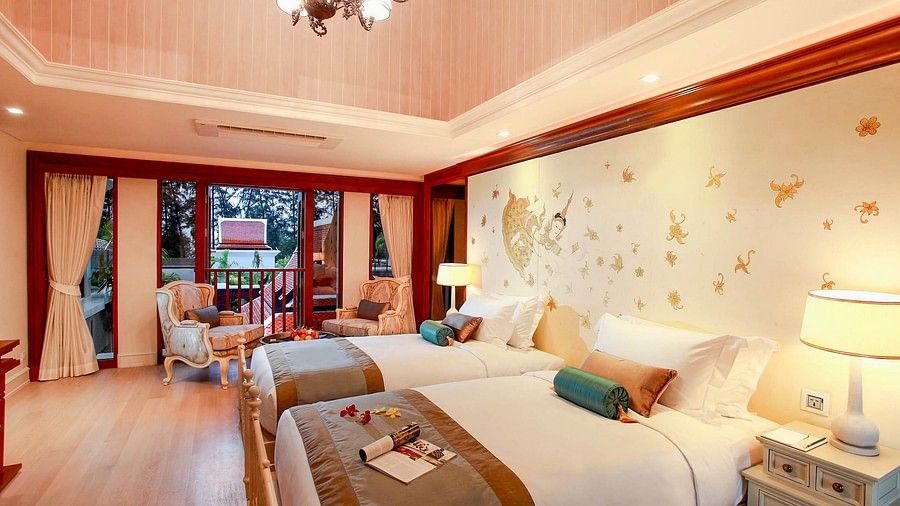 image of a bedroom with plush twin beds with ample warm lighting - three bedroom private pool villa