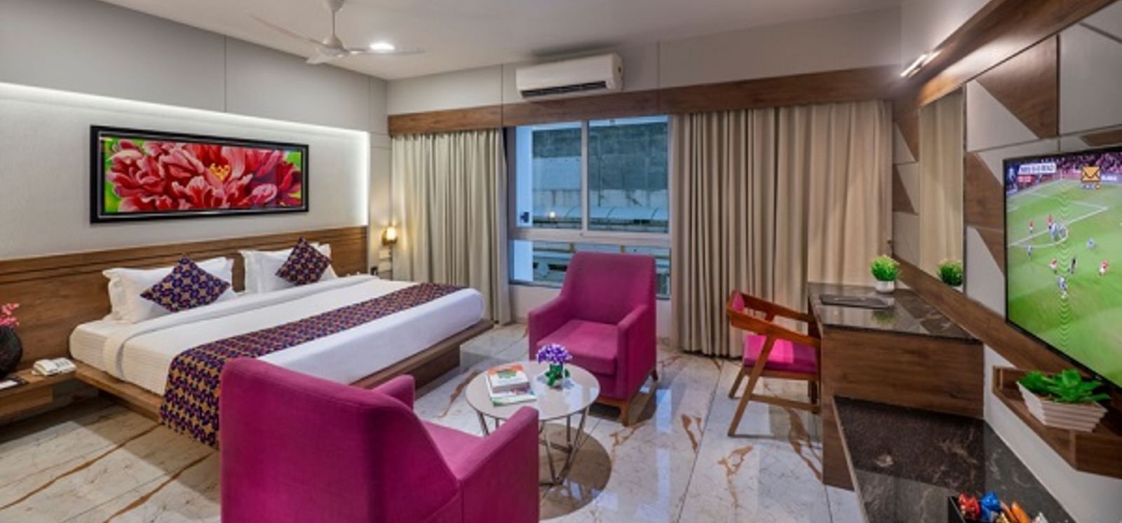 A room featuring a bed, a seating area with armchairs, and a television at Angel Lords Eco Inn Amreli.