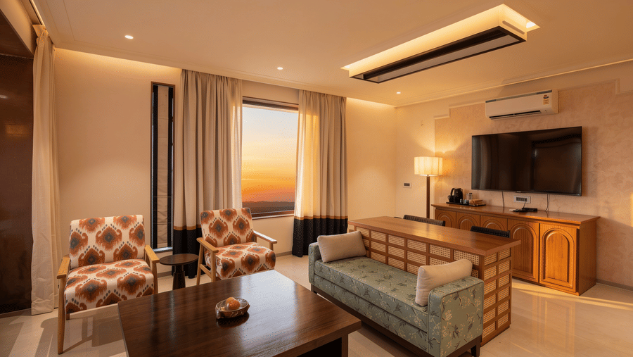 A sitting room displaying a sofa with a wooden back, 2 patterned armchairs, and a wall-mounted television at The Sierra - By The Lake.