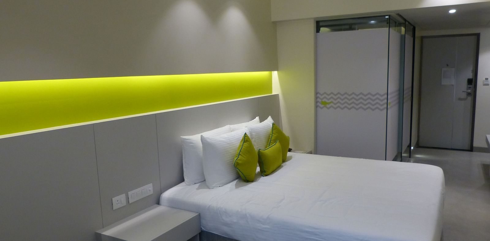 Spacious bed with headboards stretch across the wall with door way leading to the  next room