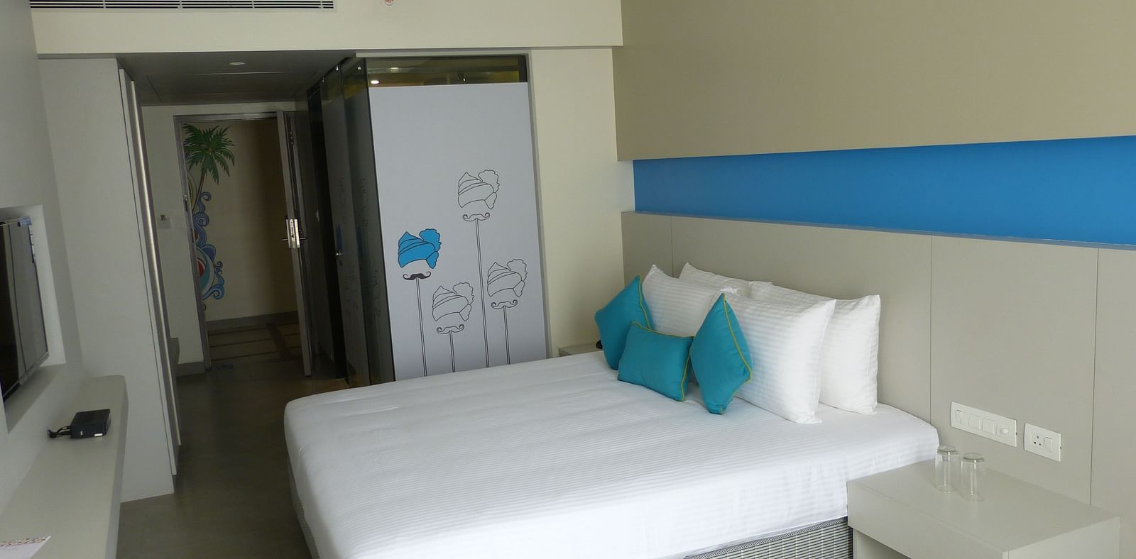 Spacious bed with headboards stretch across the wall with door way leading to the  next room