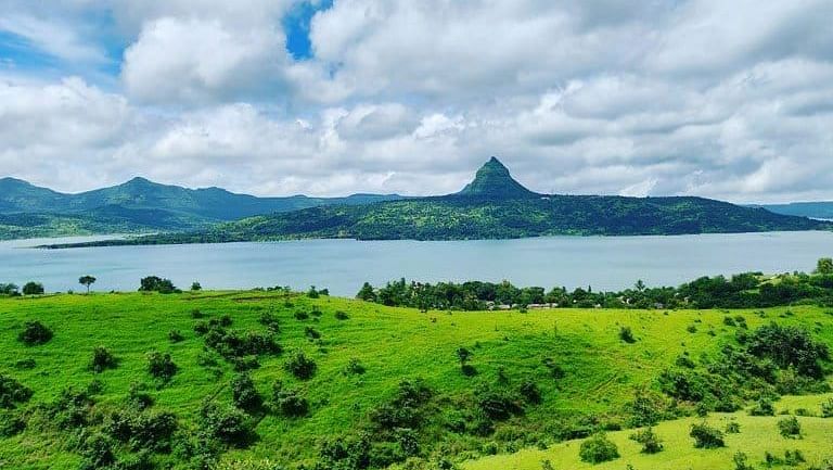 Scenic view of rolling hills and a lake under a blue sky.