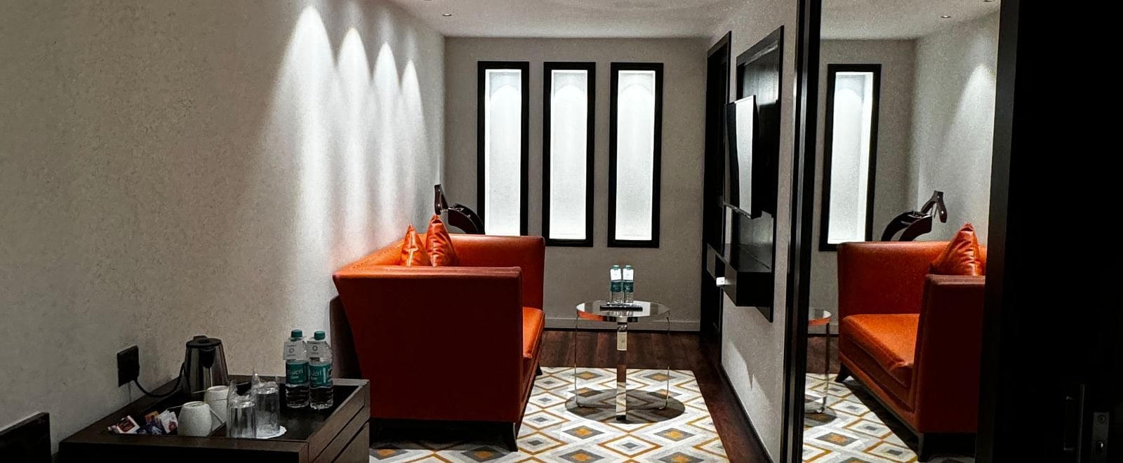 A stylish living area with a mirrored wall reflecting armchairs and a table at Cenneys Gateway.