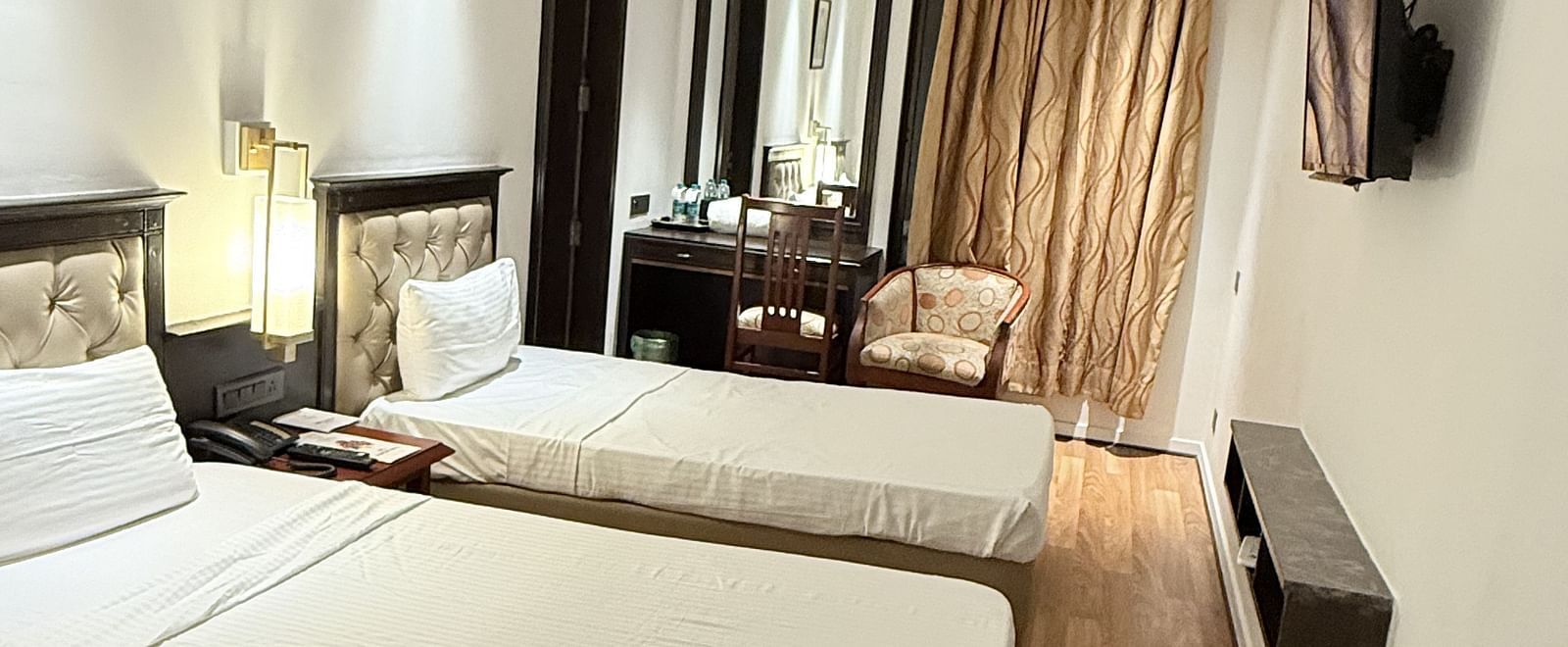 A spacious room with twin beds and a wall-mounted TV opposite them | Cenneys Gateway