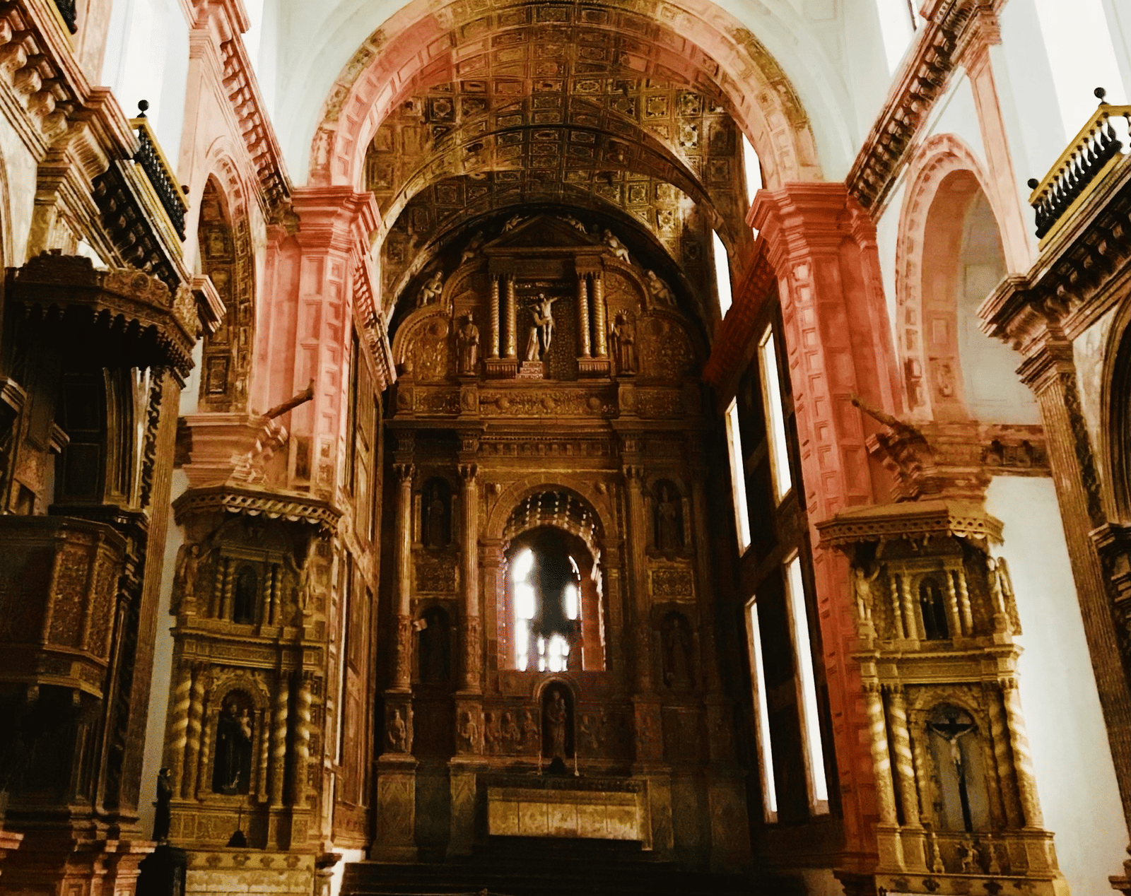 An opulent church interior with a gold-toned design and a magnificent domed ceiling.