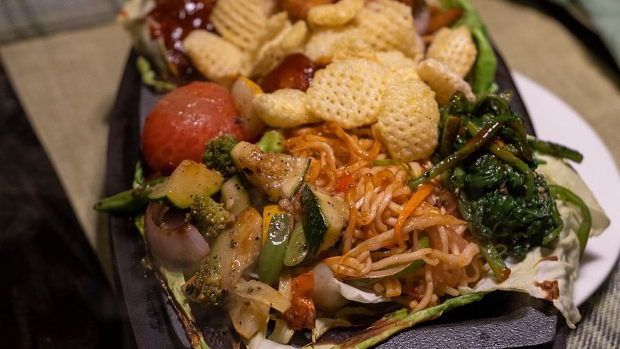 a veg cantonese dish including noodles some crisps and sauteed vegetables - beautifully served on a plate at the restaurant of - Barsana Boutique Hotel Kolkata