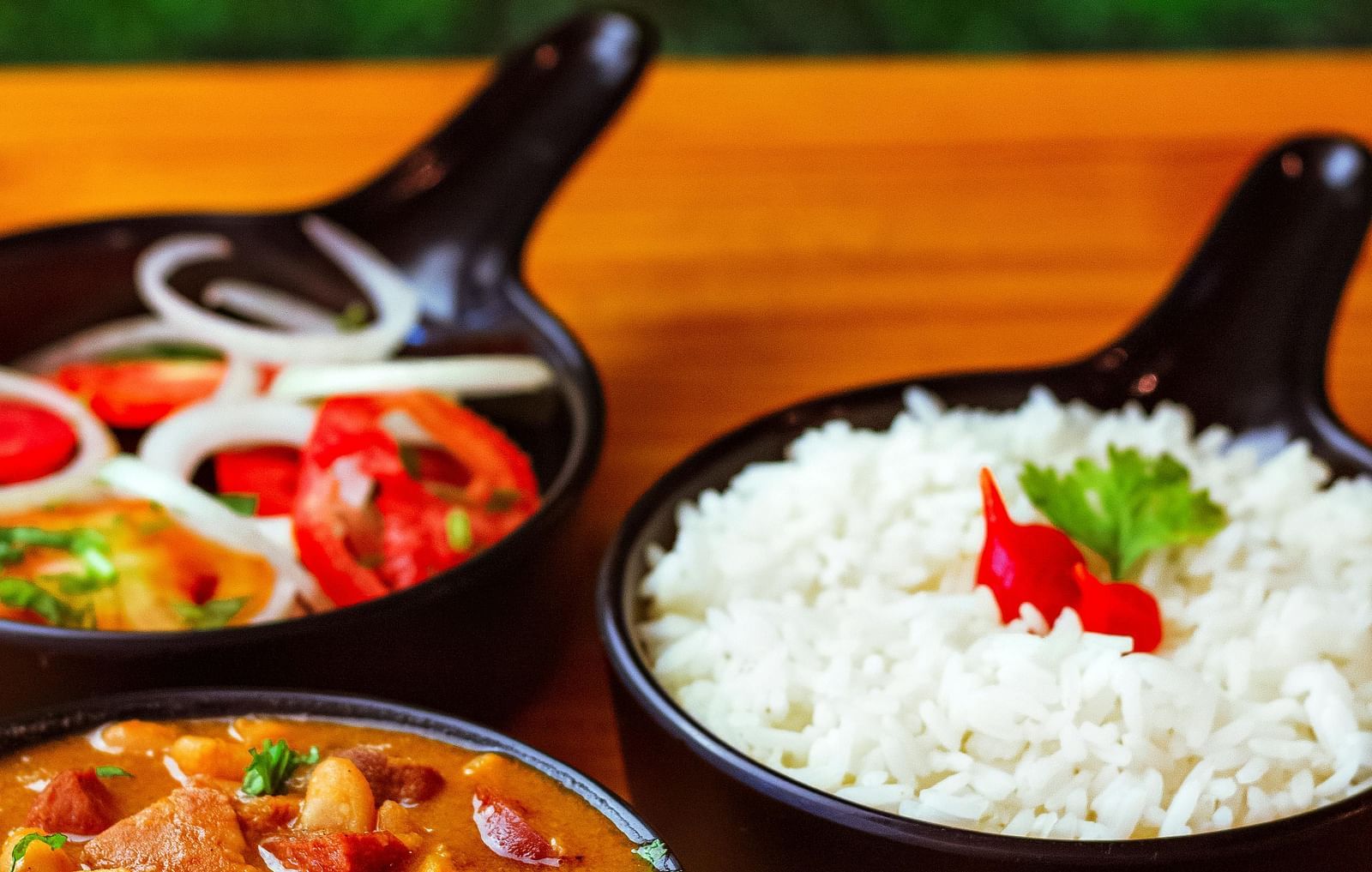 close up image of black coloured bowls with steamed rice, a side dish and some salad
