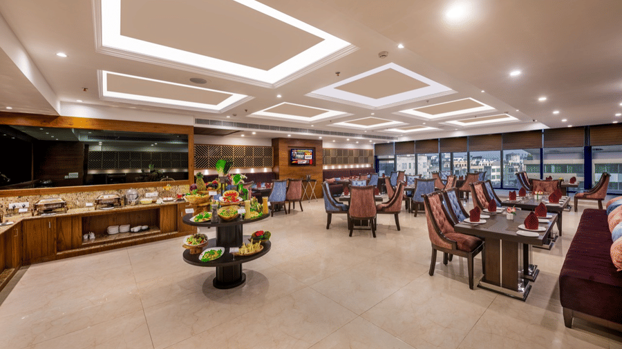 Elegant restaurant interior with multiple dining tables, cushioned chairs, and modern ceiling lighting.