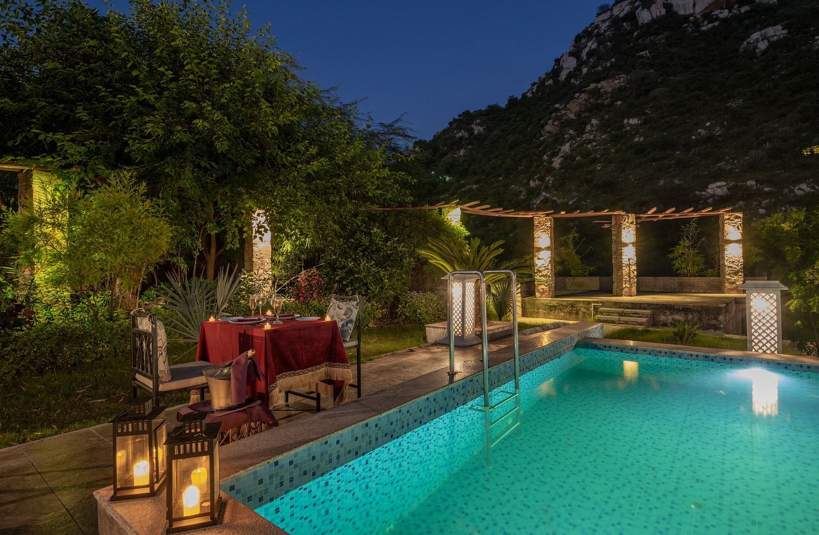 Night view of a swimming pool with a dining table and two chairs set beside it at Valley by Grassfield.