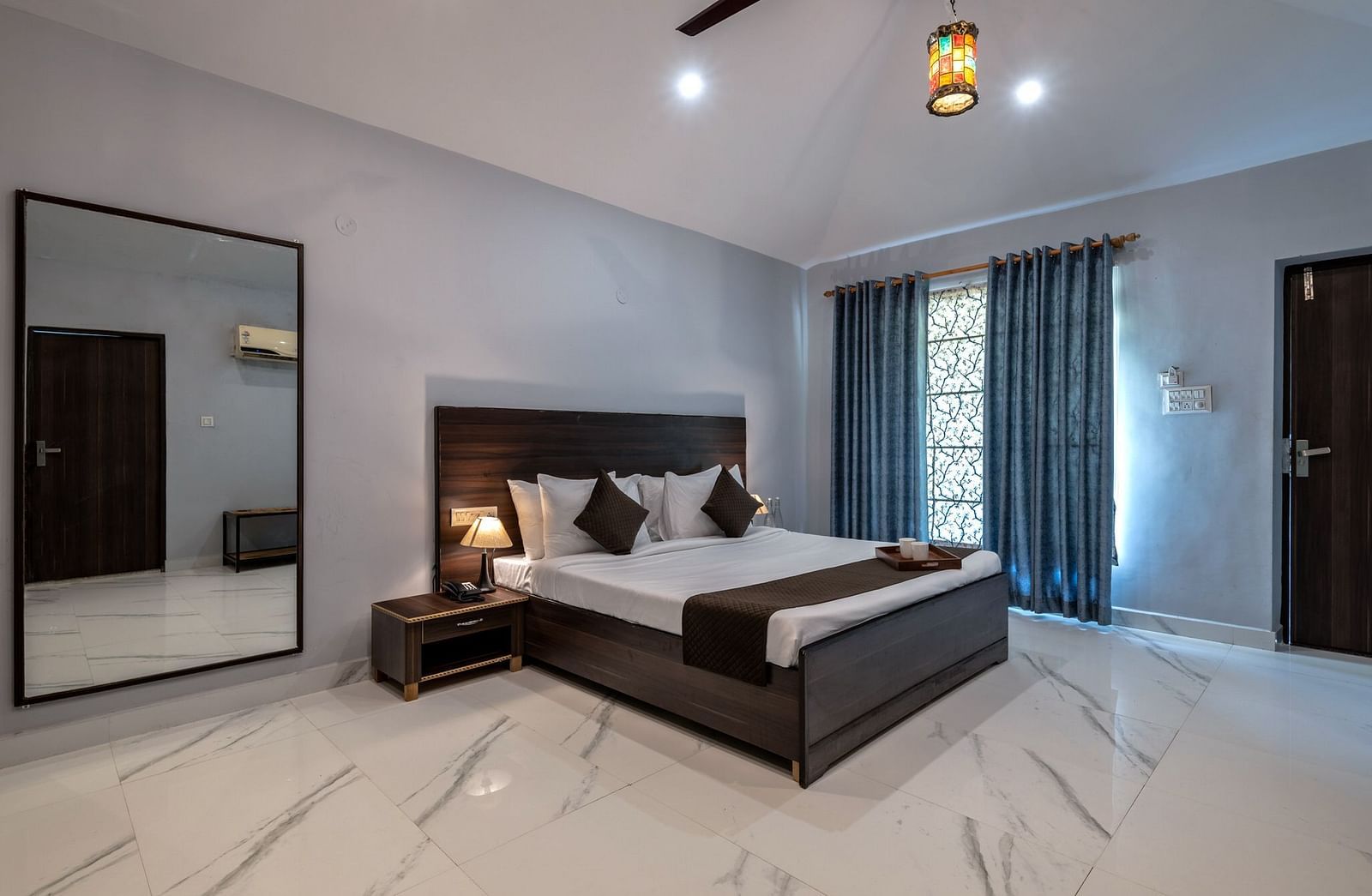 Side view of a room with a bed and a large mirror beside it at Valley by Grassfield.