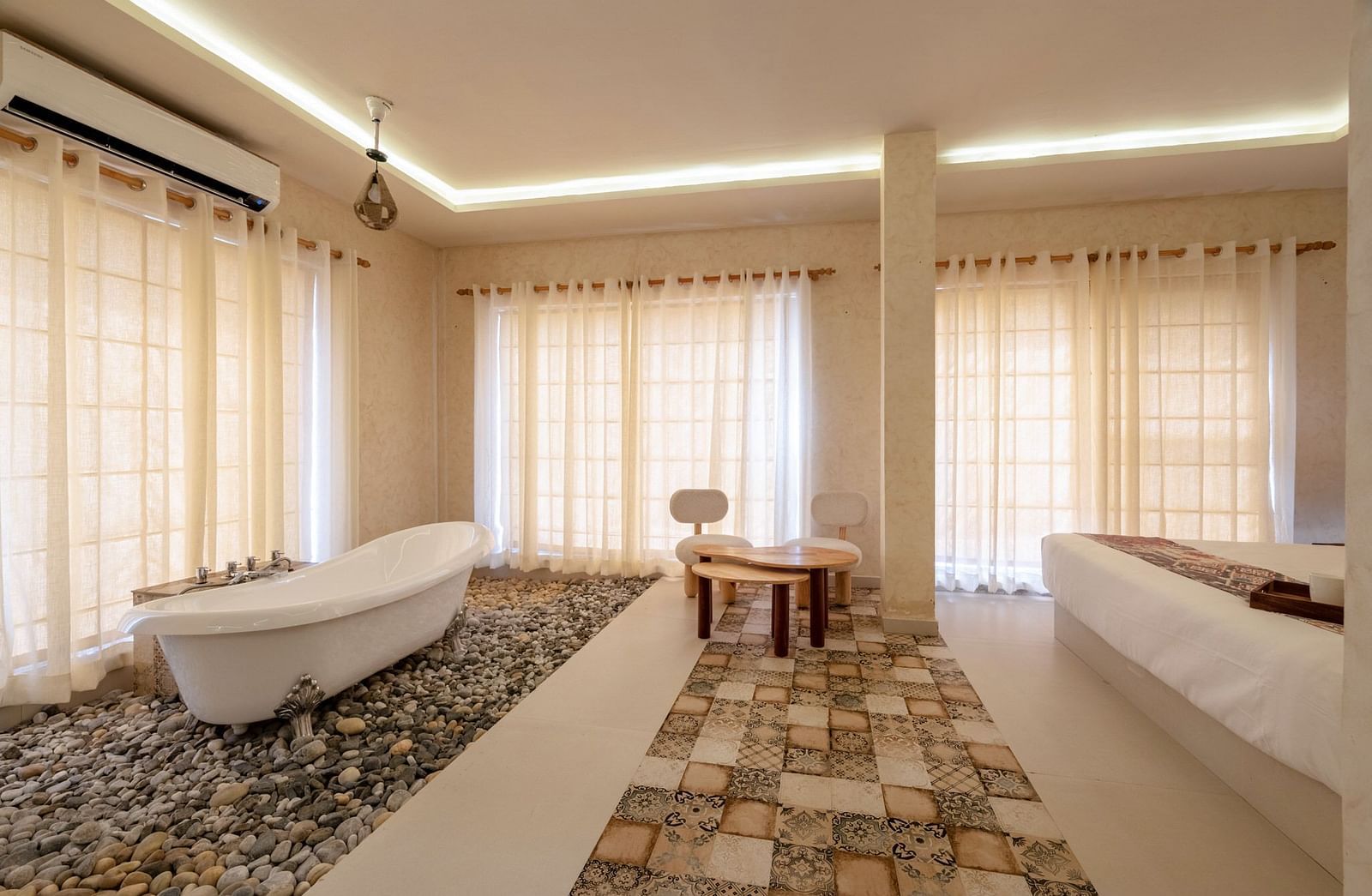 A room featuring a bed and a bathtub set on pebbles at Valley by Grassfield.