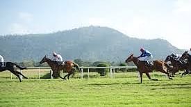 people riding horsed on a green field surrounded by lush green mountains