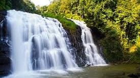 Wide waterfall cascading over a rocky ledge surrounded by greenery.