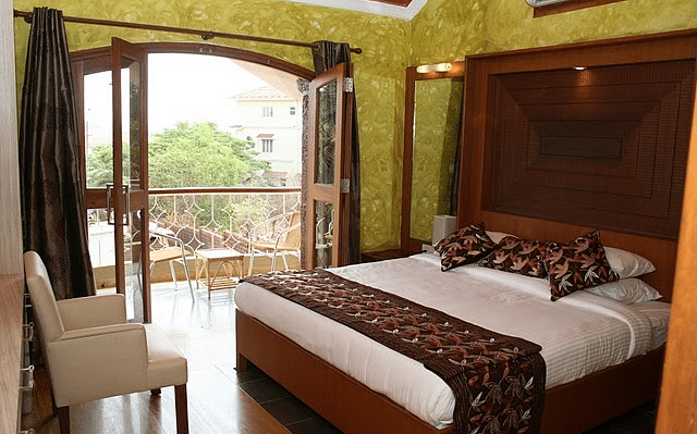 Room featuring a double bed and a balcony with seating area