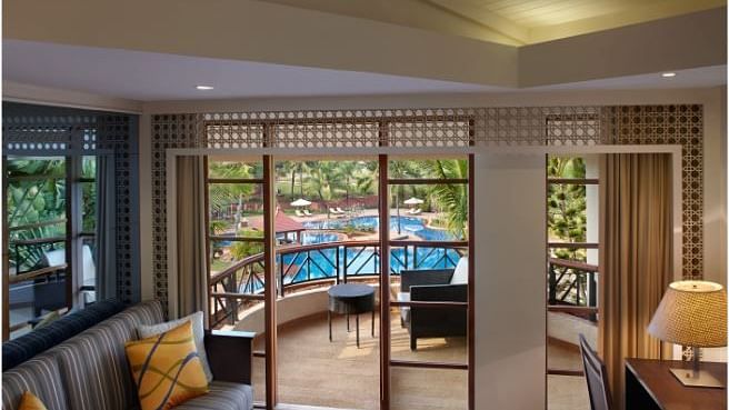 a sofa next to the balcony door inside one of the rooms - Caravela Beach Resort Goa