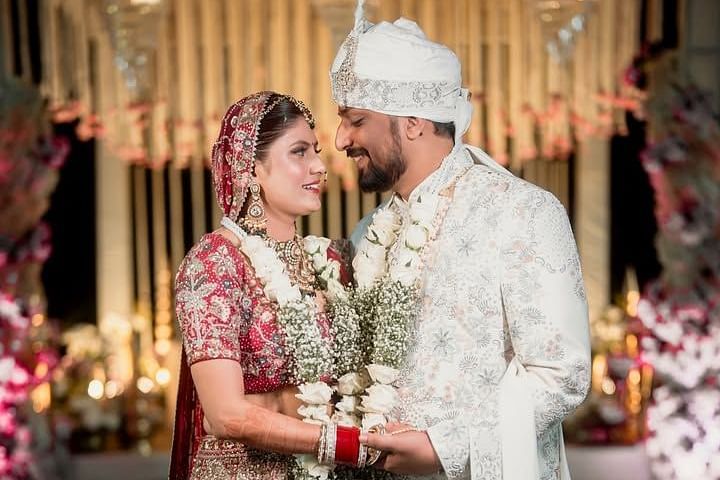A bride and groom in traditional Indian attire holding hands and exchanging garlands at their wedding ceremony. - Umaid Palace - A Lakeside Heritage Palace Resort