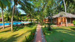 a pathway leading to the swimming pool and rooms next to many trees - Abad Harmonia, Kovalam