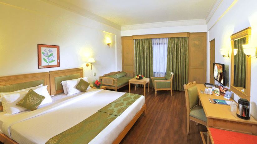 The Suite at Abad Atrium, MG Road, with a double bed, seating area, work desk and a large window.