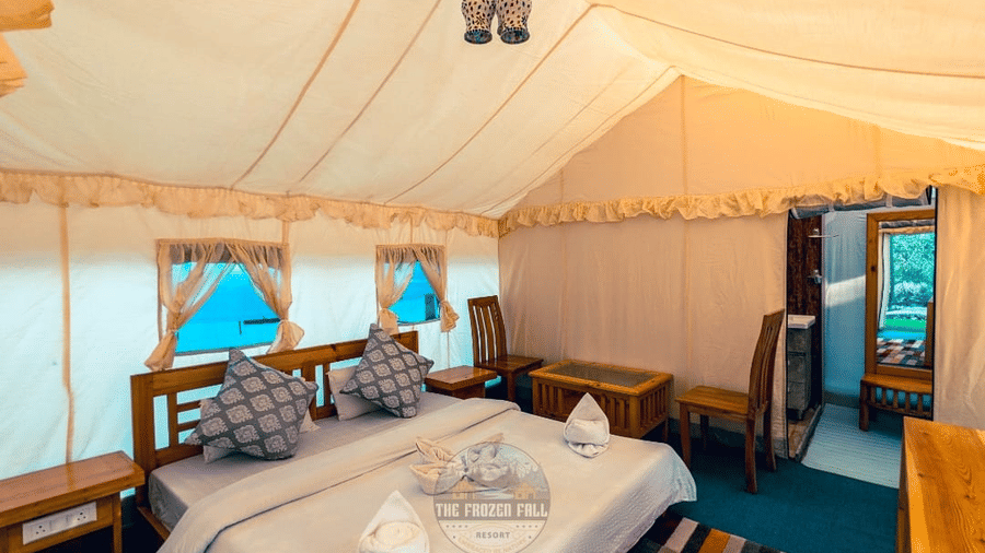 A Luxury Tent's bed setup at Dawat e Drung by FrozenFall Resort, Drung, Tangmarg, featuring a double bed with cushions and a ceiling light.