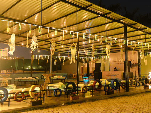 An outside view of Urban Dhaba that can be used as one of the best banquet halls in Daman with LED lights, dream catchers, and seating arrangement in view at VITS Daman Devka Beach.