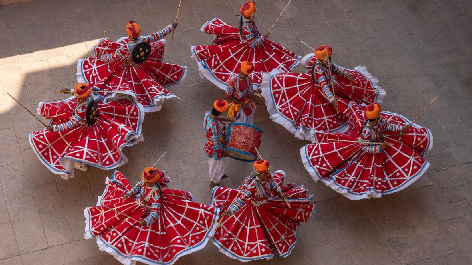 Group of Rajasthani folk dancers performing in vibrant red traditional Ghagra Choli costumes.
