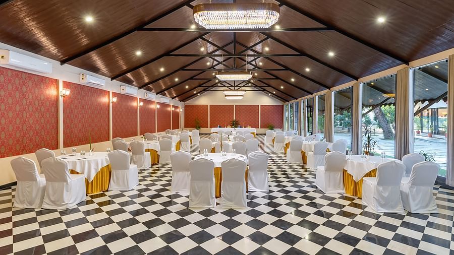 image of an expansive banquet hall with black and white marble flooring with chairs and tables arranged systematically at aranya vilas