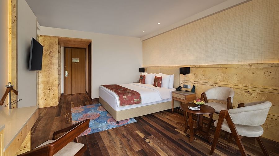 INFINITEA executive room with a double bed, chairs and a television at Infinitea Centric, Dharamshala