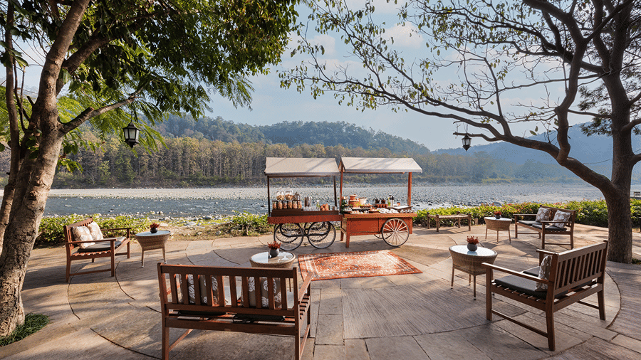 Open-air seating area with wooden tables and chairs overlooking the river at The Riverview Retreat, Corbett.