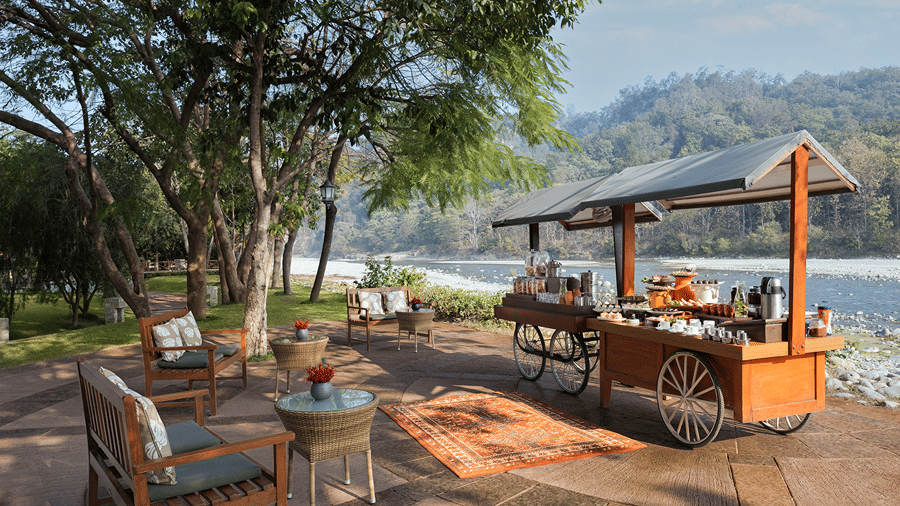 Outdoor dining area with a wooden service counter and seating overlooking the river at The Riverview Retreat, Corbett.