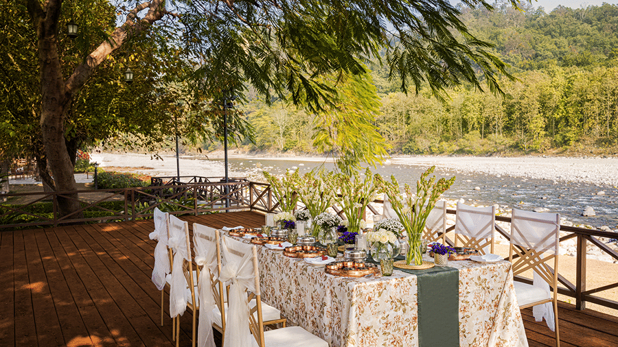 Outdoor dining table arranged with tableware and floral decorations overlooking the river at The Riverview Retreat, Corbett.