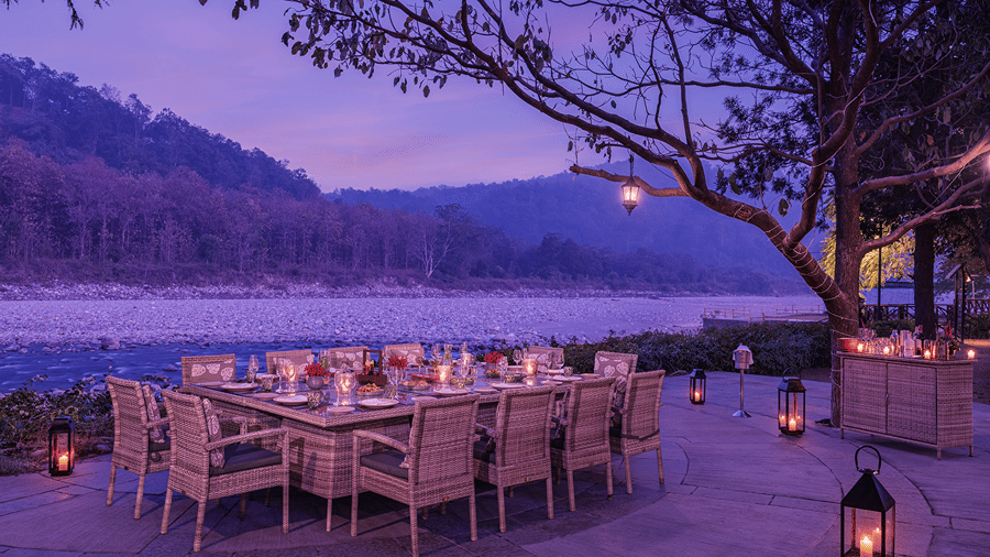 Riverside dining setup with tables and chairs illuminated by lanterns at The Riverview Retreat, Corbett.