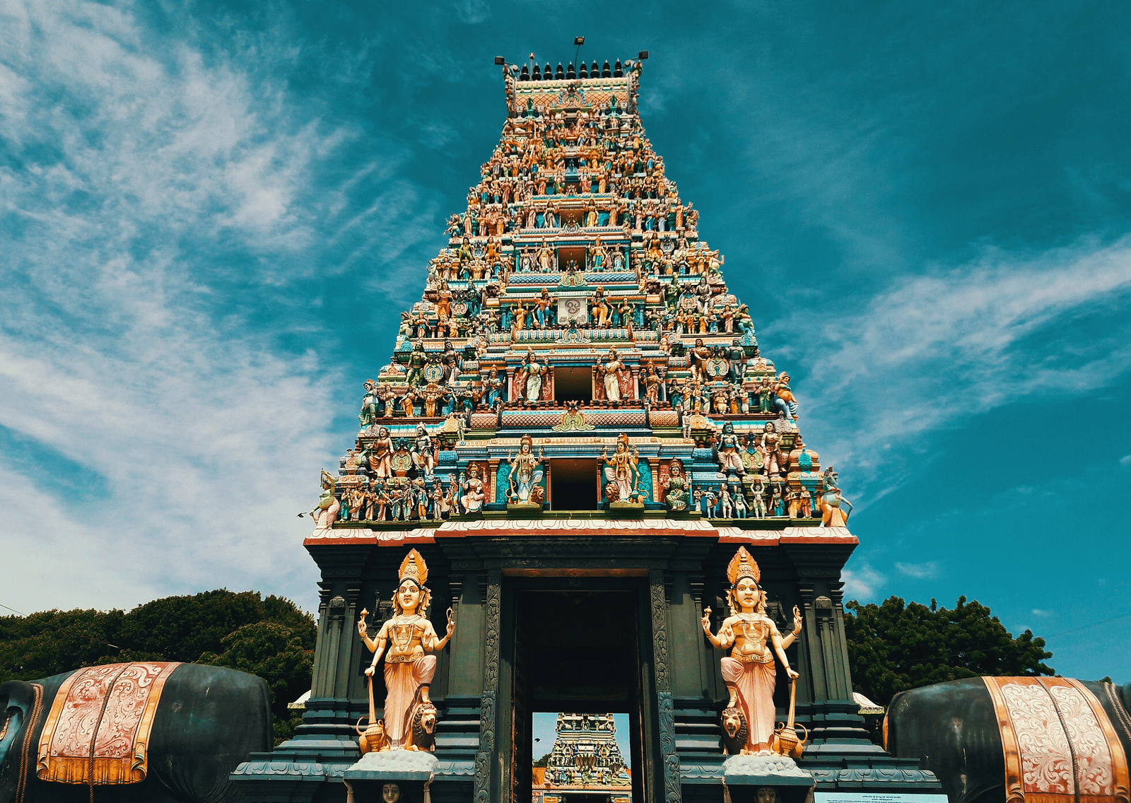 A temple with intricate carvings on its roof and two hindu deities on either side of the entrance.