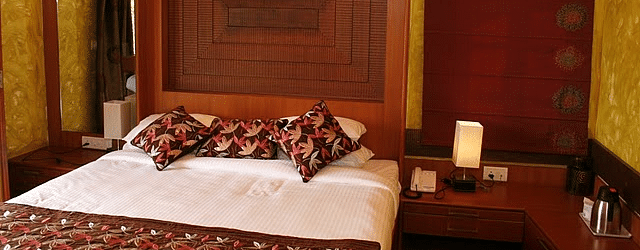Room featuring a comfy king bed with wooden headboard and nightstand