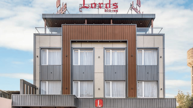 A modern, multi-storey hotel building with a large red logo on the exterior.