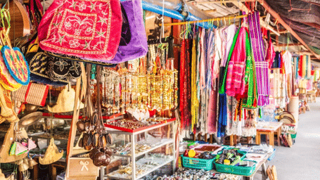 A colourful market stall selling bags, scarves, and other handicrafts at a street market in Chiang Mai, Thailand.
