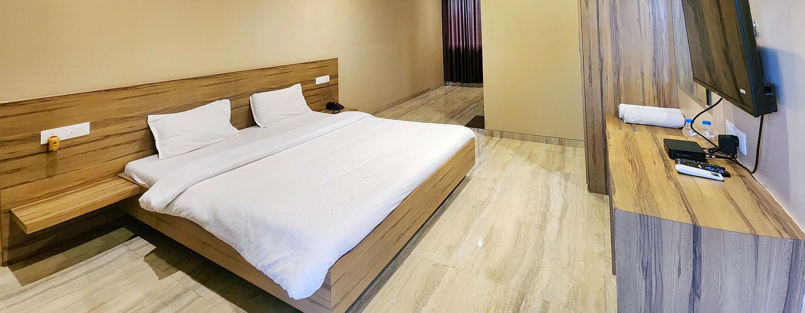 Pool View Standard Room at The Kanila Resort with a queen sized bed, a nightstand, a TV, and a desk. 