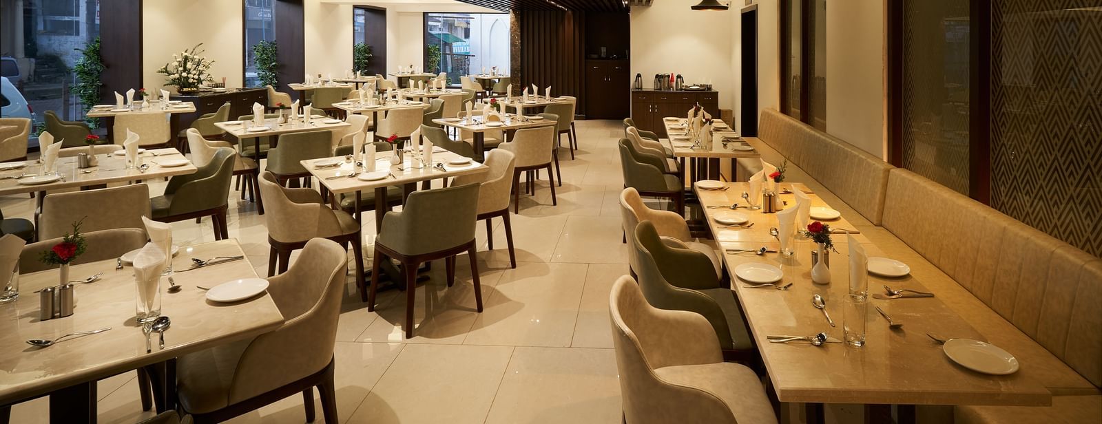 Spacious dining area with tables and chairs on one side, and seats along the wall on the other at The Hamuse Hotel, Kodaikanal.