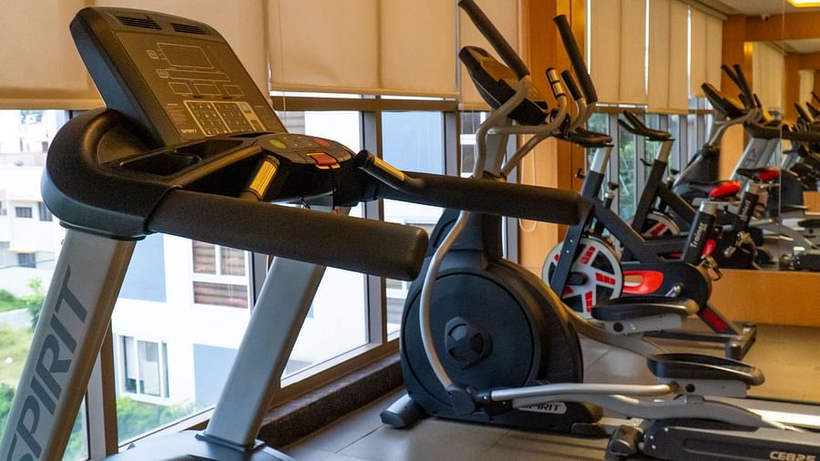 Exercise equipment, including a treadmill, in a brightly lit room.