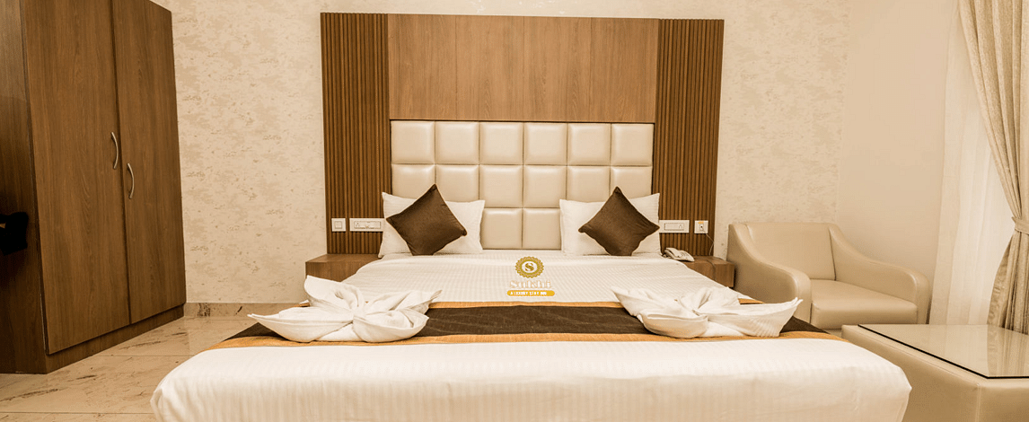 Super Deluxe Room featuring a king size bed with a white duvet and pillows, a wooden headboard.- Sukhi - A Luxury Stay Inn, Chikkamagaluru