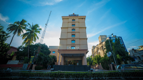 Facade view of Raj Park Hotel in Alwarpet with blue sky in the background.
