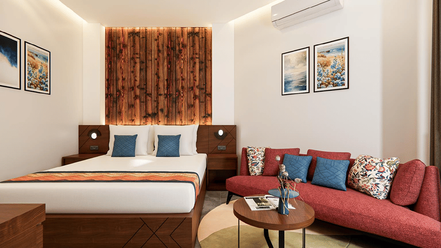Spacious bedroom interior featuring a textured dark wood headboard wall, king bed, red sofa lounge area, and framed wall art.