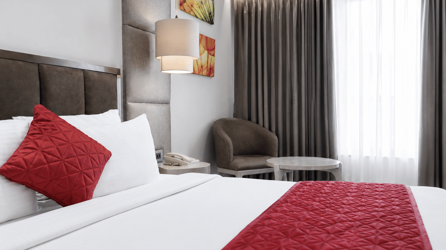 Premium Room with a king bed, vibrant red accents, and cozy seating chairs at Hotel Saket 27, offering a warm and inviting stay.
